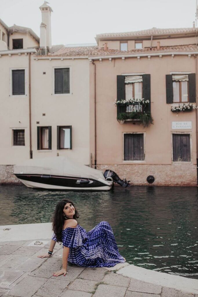 Rachel Rofé siting near the waters edge in Italy.