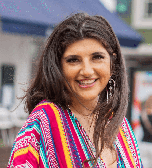 Image of Rachel Rofé standing wearing a colorful dress.